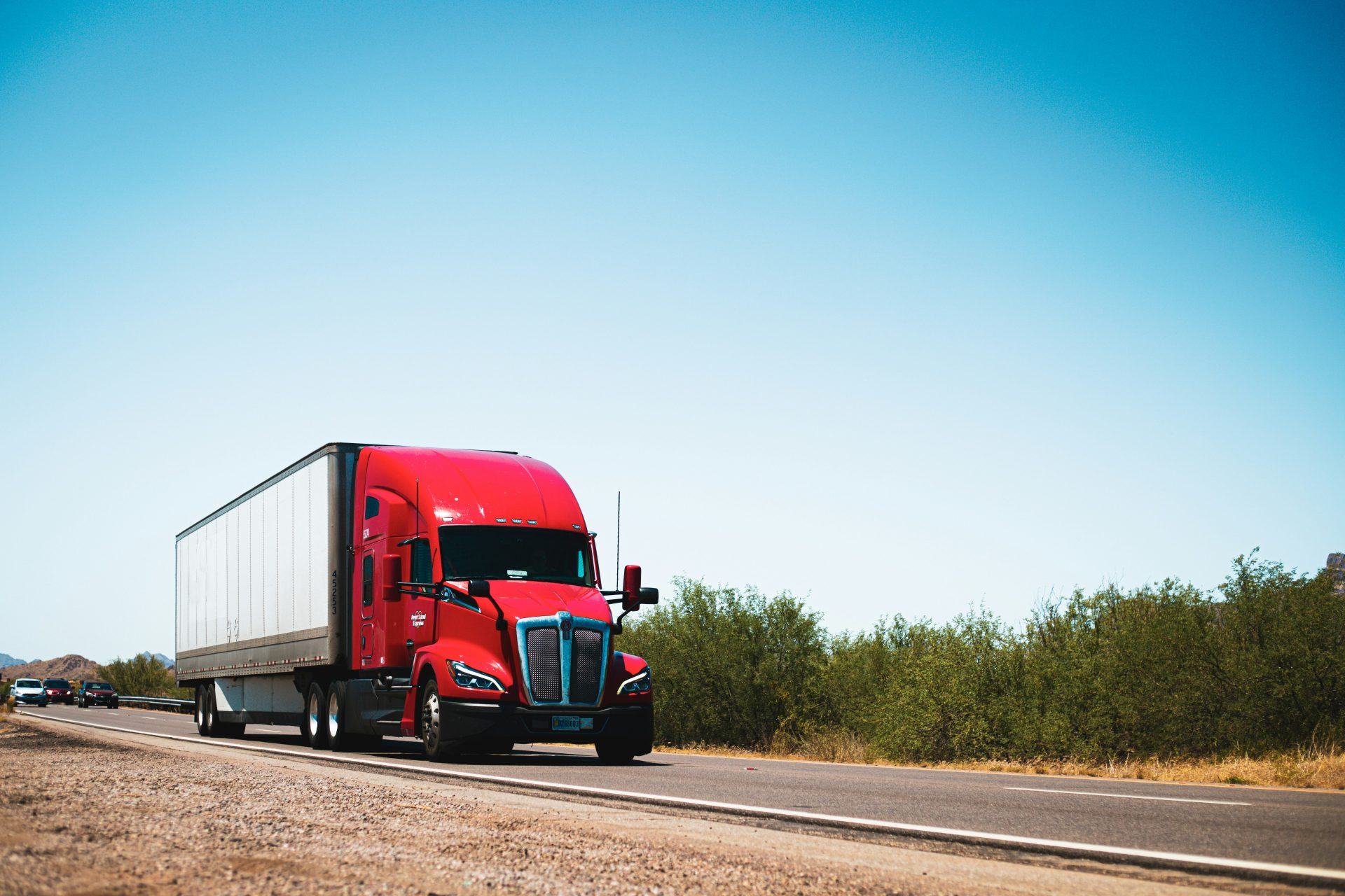 Red semi-truck driving on open highway